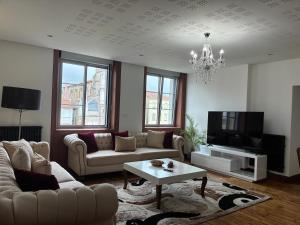 ein Wohnzimmer mit Sofa und Fernseher in der Unterkunft Le Savoyard in Saint Etienne