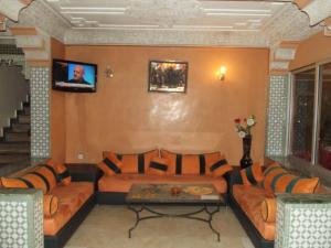 a living room with couches and a tv on a wall at Hotel Al Kabir in Marrakech