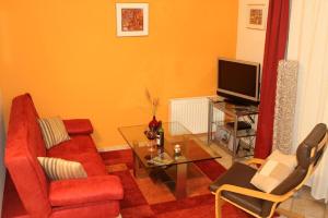 a living room with a red couch and a tv at Ferienwohnung Südblick in Groß Zicker in ruhiger Lage mit Terrasse und Meerblick in Groß Zicker