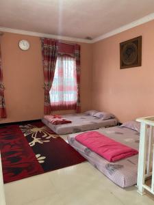 two beds in a room with a window at Homestay Dieng Mahameru in Kejajar