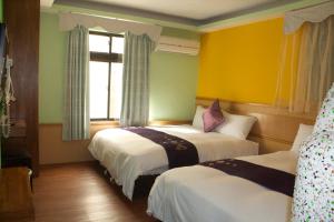two beds in a room with yellow and green walls at 文風小築Wen-Feng House-免費停車 in Kenting +17 photos