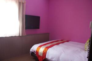 a bedroom with pink walls and a bed and a tv at 文風小築Wen-Feng House-免費停車 in Kenting
