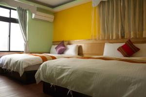 two beds in a hotel room with yellow walls at 文風小築Wen-Feng House-免費停車 in Kenting