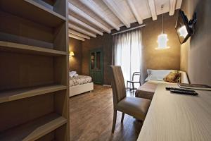 une chambre d'hôtel avec un bureau et un lit et une chambre dans l'établissement Notti O' Tunn Luxury Rooms in centro, à Geraci Siculo