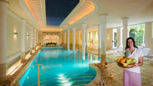a woman holding a bowl of fruit next to a swimming pool at Hotel Victoria & Iside Spa in Turin