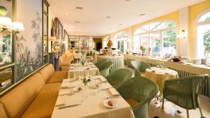 um restaurante com mesas brancas e cadeiras verdes em Hotel Victoria & Iside Spa em Turim