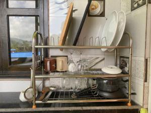 a kitchen shelf with plates and utensils on it at Dulcify cottage sarangkot in Pokhara