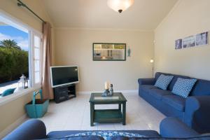 a living room with a blue couch and a tv at Villa Pippa in Puerto del Carmen