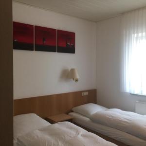 two beds in a room with red cabinets and a window at Gasthaus Keglerklause in Schwieberdingen
