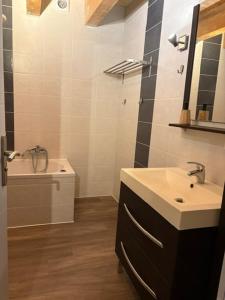 ein Badezimmer mit Waschbecken, Spiegel und Badewanne in der Unterkunft Loft-style apartment, Pierrelatte in Pierrelatte