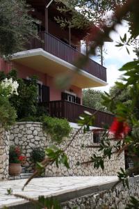 a building with a balcony and a stone wall at Evridiki's Villas in Agios Nikitas