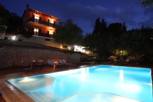 a large swimming pool in front of a building at night at Evridiki's Villas in Agios Nikitas