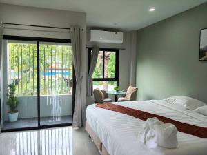 a bedroom with a bed and a large window at Le Wadee Residence in Bang Tao Beach