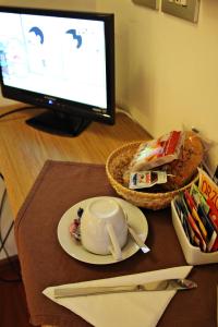 a desk with a computer monitor and a bowl and a plate at Primavera Mini Hotel in Perugia