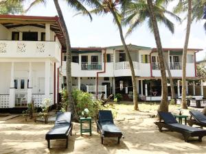 a building with chairs and palm trees in front of it at Dephani Beach Hotel in Negombo