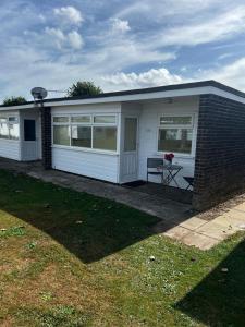 a small white house with a table in a yard at 186 Sundowner Holiday Park in Hemsby