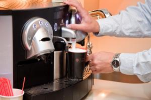 a person is making a drink in a coffee machine at Inn at St. Botolph in Boston