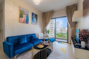 a living room with a blue couch and a large window at Masteri Thao Dien Riverside Apartment in Ho Chi Minh City
