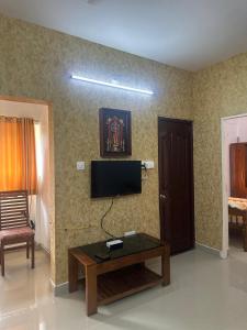 a living room with a tv and a coffee table at Guruvayur Soorya Madhavam Apartment in Guruvāyūr