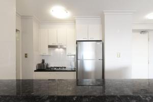 a stainless steel refrigerator in a kitchen with white cabinets at Cosmopolitan Charm in Central Sydney in Sydney