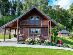 a log cabin with a porch and flowers in front of it at Leśny Zakątek in Bezmichowa Dolna