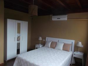 1 dormitorio con 1 cama blanca, 2 mesas y ventilador en Finca Esperanza en Yaiza