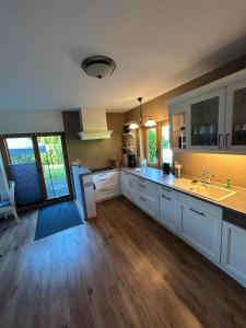 a large kitchen with white cabinets and wooden floors at Nordheideblockhaus in Asendorf +18 photos