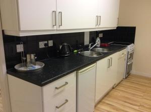 a kitchen with white cabinets and a black counter top at Tansterne Grange in Aldbrough