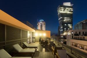 a balcony with chairs and tables on a building at night at Lily & Bloom Boutique Hotel in Tel Aviv