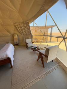 ein Schlafzimmer in einem Zelt mit einem Bett und einem Tisch in der Unterkunft Sunset Domes Premium in Badīyah