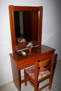 een houten bureau met een spiegel en een stoel bij Johny's Studios in Prinos