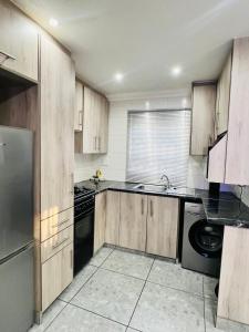 a kitchen with wooden cabinets and a dishwasher at Affordable Modern Stay in Vanderbijlpark +11 photos
