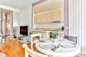 a kitchen and dining room with a white table and chairs at Appartement Quartier Arc de Triomphe Free Netflix in Paris +3 photos