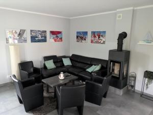 a living room with a black couch and a fireplace at Villa Bella Zastan Sauna & Jacuzzi in Międzywodzie