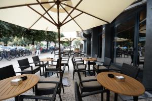 eine Reihe von Tischen und Stühlen mit Sonnenschirmen auf einer Straße in der Unterkunft Appartamenti Porta Nuova 80 in Verona