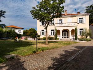 une maison blanche avec un arbre en face d'une rue dans l'établissement La Finestra sul Corso, Gorizia, à Gorizia