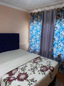 卢萨卡LaJoy Lodge的一间卧室配有床和鲜花窗帘 更多16张照片