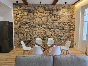 a dining room with a stone wall and a glass table and chairs at Apartamento Plaza de Armas in Ferrol