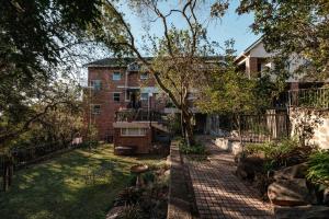 een appartementencomplex met een hek en een tuin bij The Green Lizard Guesthouse in Nelspruit