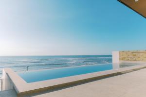 a swimming pool with the ocean in the background at Palms La Union Beachfront Suites in San Juan