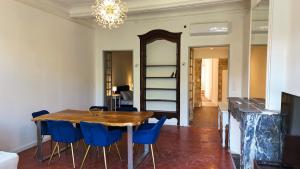 a dining room with a wooden table and blue chairs at Magnifique appartement cours Jean Jaurès Climatisée in Pézenas +2 photos