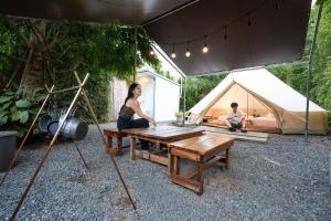 a woman sitting on a table in front of a tent at Chavallee Campground in Ban Tha Chang +13 photos
