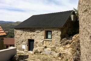 a stone house with a black roof at Retiros do Vale in Vila Real