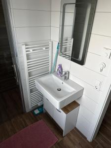 a white bathroom with a sink and a mirror at Creek House in Müllheim +25 photos