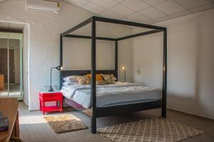 a bedroom with a black canopy bed with a red nightstand at Baagh-Bohemian 6BHK Farmhouse, Jagatpura, Jaipur in Jaipur