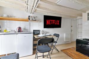 a kitchen with a table and chairs and a television on the wall at Studio Appartement Quartier Saint-Michel Notre-Dame 3 Free Netflix in Paris +2 photos