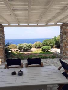 a patio with a white table and chairs and the ocean at Villa Heliophilia in Koundouros