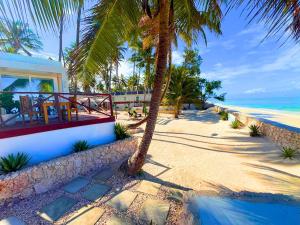 een huis op een strand met palmbomen en de oceaan bij The Zanzibar Beach House-North in Bwejuu