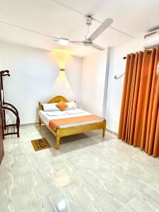 a bedroom with a bed with orange curtains at Akshaya Villa Trincomalee in Trincomalee