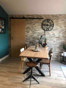 ein Esszimmer mit einem Tisch und einer Uhr an einer Ziegelmauer in der Unterkunft Appartement proche des plages in Bidart
